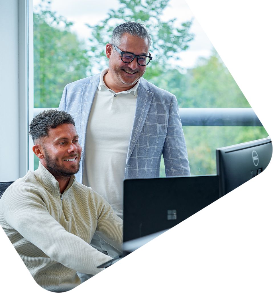 Twee collega's bespreken Dynamicweb PIM-oplossingen achter een computer